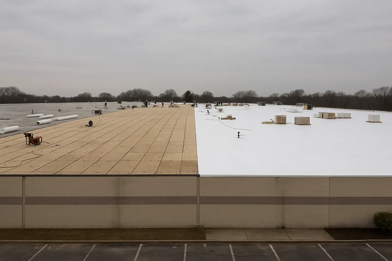 White TPO membrane being installed over a flat commercial roof in the Houston area